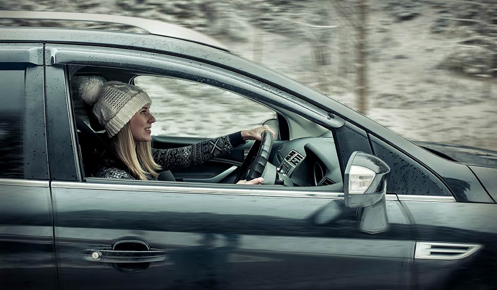 Woman in a bobble hat driving in a snowy scene