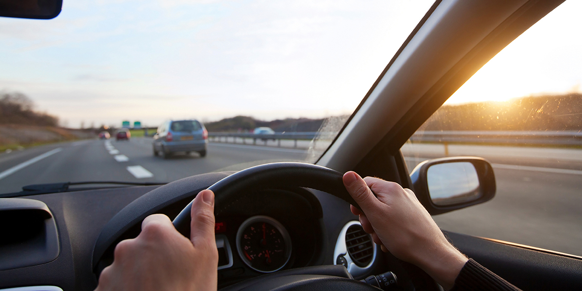 Close up of hands on steering wheel, driving on motorway - driving skills