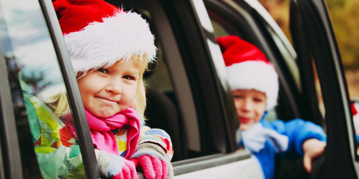 Photo of kids in Santa hats looking out of car windows