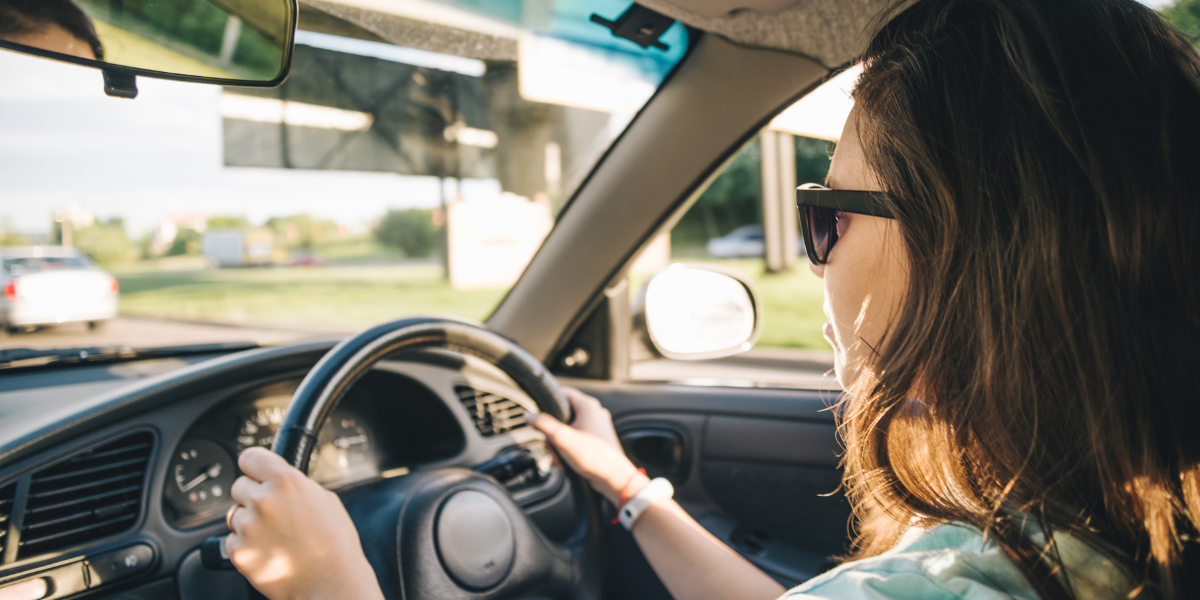 Photo of a lady driving in a car on a summer day